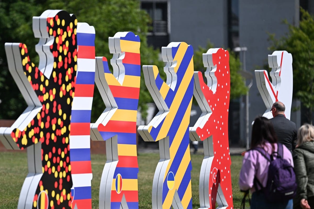 Personas caminan junto a figuras con forma de oso con los colores de las naciones participantes en el próximo Campeonato Europeo de Fútbol UEFA Euro 2024 en Berlín, el 13 de junio de 2024. (Foto de RALF HIRSCHBERGER / AFP)